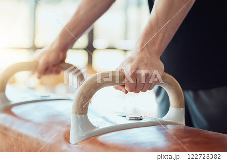 Hands of man gymnast training on pommel horse for fitness, strong balance and flexibility workout sport goal. Sports athlete on exercise or practice gym equipment for better cardio performance Hands of man gymnast training on pommel horse for fitness, strong balance and flexibility workout sport goal. Sports athlete on exercise or practice gym equipment for better cardio performance 122728382