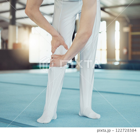 Gym, sport and injury of a professional gymnast suffering from leg pain or ache during training indoors. Sore knee, legs and muscle from intense athletic practice or workout exercise for competition. 122728384