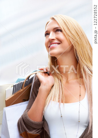 Happy woman smile after retail shopping for fashion sale and holding bags in an urban city. Exploring different store and boutique in town and looking excited with clothing choice and purchase 122728552