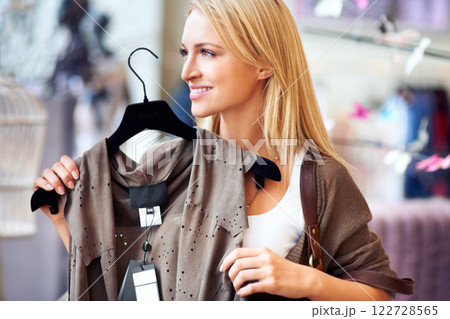 Woman shopping for clothes in a fashion store on holiday. Young trendy retail customer looking for an affordable used shirt at boutique, market or charity shop. Stylish lady choosing a modern outfit Woman shopping for clothes in a fashion store on holiday. Young trendy retail customer looking for an affordable used shirt at boutique, market or charity shop. Stylish lady choosing a modern outfit 122728565