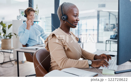 Black call center, telemarketing, and customer service consultant typing on computer for database information a busy office. Contact us and crm agent offering support, help and service with a smile 122728622