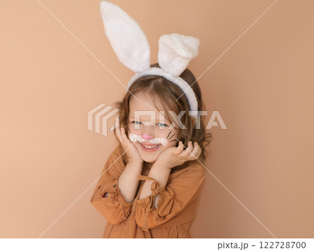 A sweet smiling little girl dressed up as an Easter bunny with a painted face A sweet smiling little girl dressed up as an Easter bunny with a painted face 122728700