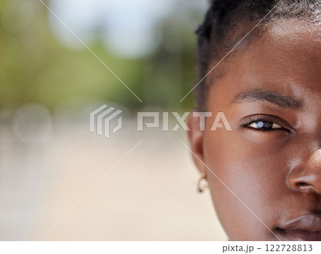 Serious face portrait of a woman with clear skin outdoors in natural light and background. African, female eye and head zoom focus isolated in nature with a confident and vision empowerment look 122728813