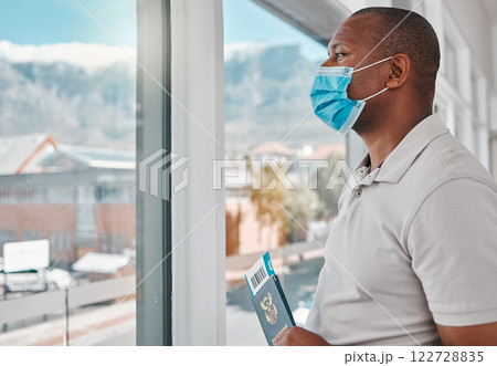 Man at airport with covid passport, travel visa and mask for plane flight of international immigration. Tourist, traveller and passenger waiting at window for airplane departure in corona pandemic Man at airport with covid passport, travel visa and mask for plane flight of international immigration. Tourist, traveller and passenger waiting at window for airplane departure in corona pandemic 122728835