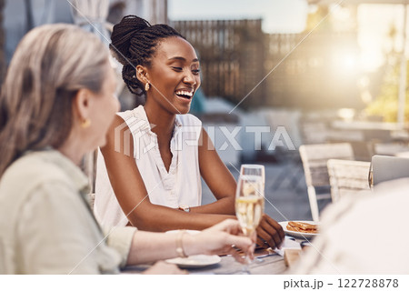 Champagne, celebration and happy women at a restaurant or social event eating at a table with lens flare and fine dining background. Black woman with a smile having food and conversation with friends 122728878