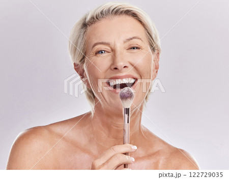 Beauty, makeup skincare with a senior model holding a blusher brush in studio against a gray background. Portrait of an elderly woman with a smile posing for wellness, healthcare and cosmetics 122729035