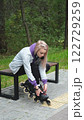 Cute blonde puts on roller skates. She feels free and light while roller skating alone in the city park. Stunning Caucasian woman with a beautiful figure uses roller skates for outdoor sports. 122729259