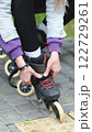 Cute blonde puts on roller skates. She feels free and light while roller skating alone in the city park. Stunning Caucasian woman with a beautiful figure uses roller skates for outdoor sports. 122729261