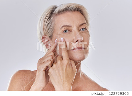 Acne or pimple popping senior woman while doing a skincare beauty treatment for healthy and clear skin. Portrait of happy old, mature or elderly female squeezing a spot on her face 122729306