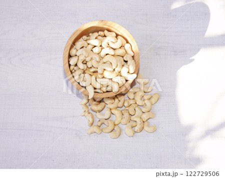 Cashew nuts in wooden bowl on white table with sunshine. Healthy food. Cashew nuts in wooden bowl on white table with sunshine. Healthy food. 122729506