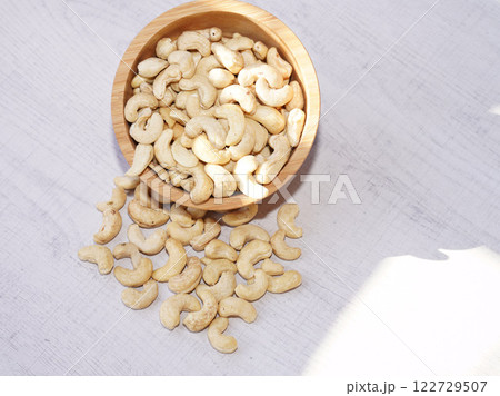 Cashew nuts in wooden bowl on white table with sunshine. Healthy food. 122729507