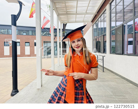 Cute child little girl student in school uniform having fun after graduation ceremony in school yard 122730515
