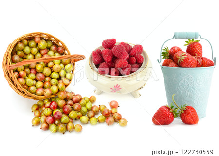 Ripe raspberries in a porcelain bowl, strawberries in decorative bucket and gooseberries in a wicker basket isolated on white. Collage. Ripe raspberries in a porcelain bowl, strawberries in decorative bucket and gooseberries in a wicker basket isolated on white. Collage. 122730559