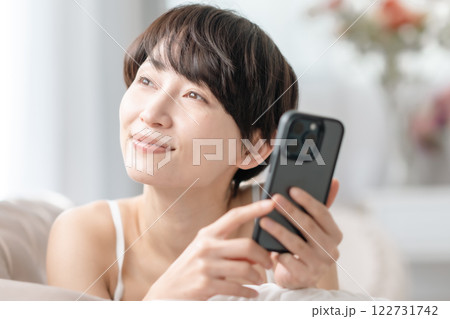 スマホを見て笑顔になるミドルの女性 スマホを見て笑顔になるミドルの女性 122731742