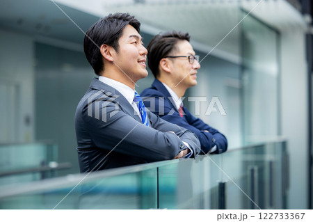 オフィスの廊下で話をする上司と部下の男性 オフィスの廊下で話をする上司と部下の男性 122733367