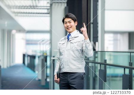 オフィスの廊下に立つ作業服の男性 122733370