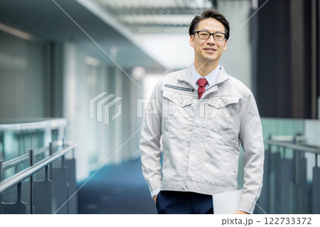 オフィスの廊下に立つ作業服の男性 122733372