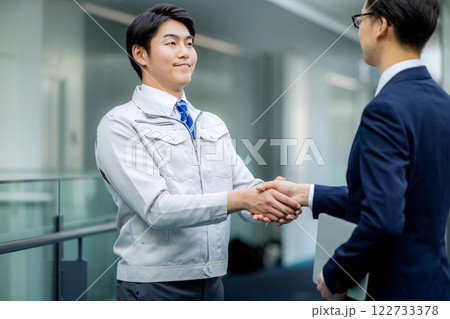 握手　作業着の男性とスーツの男性 122733378