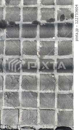 An image features textured gray cobblestone pavement with grid pattern, showcasing unique surface details and shadows An image features textured gray cobblestone pavement with grid pattern, showcasing unique surface details and shadows 122733604