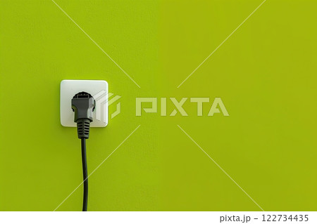 White plastic power outlet. Power socket. Brand new electrical socket isolated on a lime green wall, black single plug switched on. Renovated studio apartment power supply background. Empty copy space 122734435