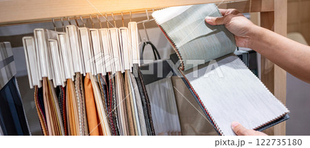 Designer hand choosing fabric pieces from fabric swatch material Designer hand choosing fabric pieces from fabric swatch material 122735180