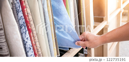 Stylist hand choosing blue fabric piece from fabric swatch material Stylist hand choosing blue fabric piece from fabric swatch material 122735191