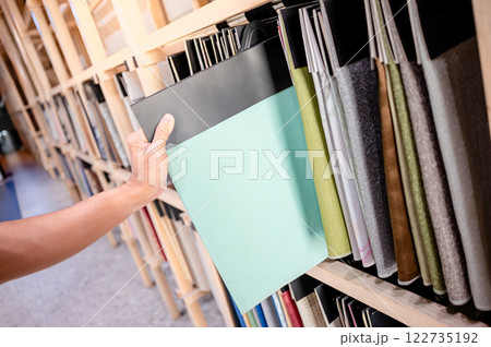 Stylist hand choosing turquoise fabric piece from fabric swatch material Stylist hand choosing turquoise fabric piece from fabric swatch material 122735192