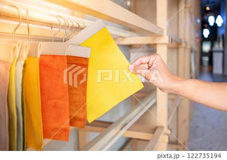 Stylist hand choosing yellow fabric piece from fabric swatch material. Upholstery sample collection 122735194