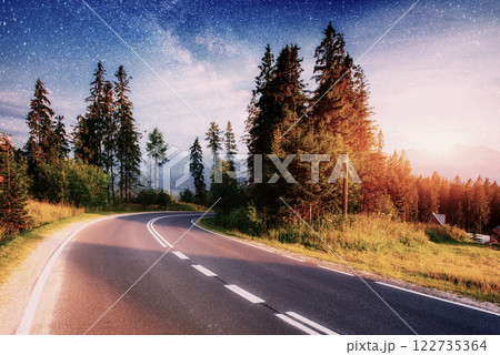 Asphalt road and lonely tree under a starry night sky and the Milky Way 122735364