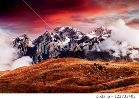Autumn landscape and snow mountains in beautiful cumulus clouds. Main Caucasian Ridge. Type Mount Ushba Mheyer, Georgia 122735405