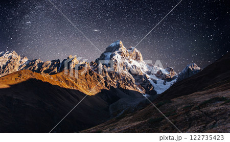 Fantastic starry sky. Autumn landscape and snow-capped peaks. Main Caucasian Ridge. Mountain View from Mount Ushba Meyer, Georgia. Europe 122735423