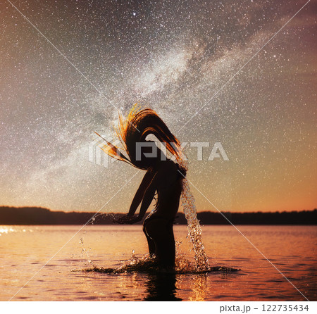 woman on water background at night sky. Fantastic starry sky and the milky way 122735434