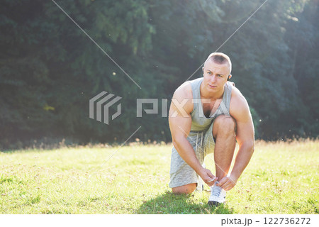 Tying sports shoe. A young sportsman getting ready for athletic and fitness training outdoors. Sport, exercise, fitness, workout. Healthy lifestyle Tying sports shoe. A young sportsman getting ready for athletic and fitness training outdoors. Sport, exercise, fitness, workout. Healthy lifestyle 122736272