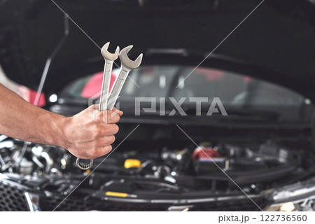 Mechanic holding pair of wrenches at the repair garage 122736560