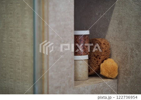 Body care products (scrubs and a natural washcloth) on the shower shelf. 122736954