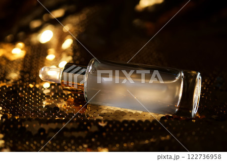 A bottle of cosmetic serum with a pipette on a festive golden background. A bottle of cosmetic serum with a pipette on a festive golden background. 122736958