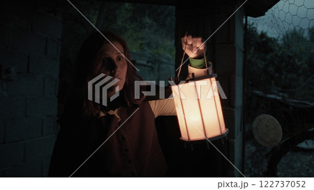 Scared Woman Explores A House In The Countryside At Night With A Lantern In Hand Scared Woman Explores A House In The Countryside At Night With A Lantern In Hand 122737052