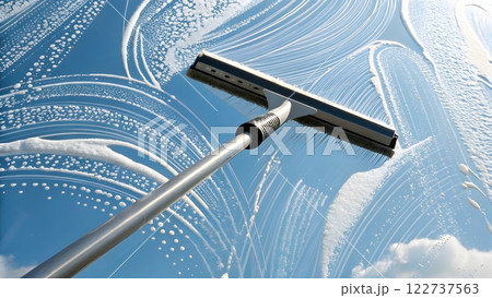 A photorealistic image of a window cleaning in progress. The image focuses on a squeegee moving across a window pane covered in soapy foam A photorealistic image of a window cleaning in progress. The image focuses on a squeegee moving across a window pane covered in soapy foam 122737563