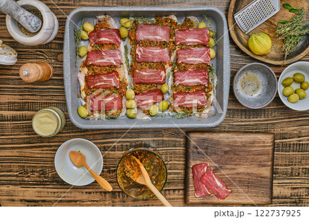 Fish fillets covered with marinade and slices of bacon in a baking tray Fish fillets covered with marinade and slices of bacon in a baking tray 122737925