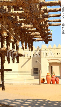 raditional desert architecture exudes rustic charm with pottery in foreground and traditional Arabic design building in background. Cultural heritage shines in harmonious scene 122738606
