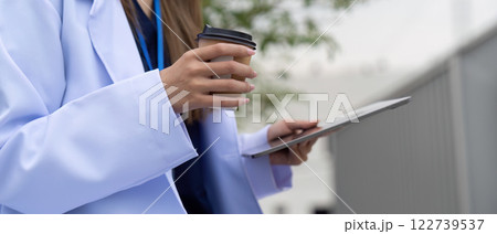 Doctor balancing coffee and tablet for efficient patient care 122739537