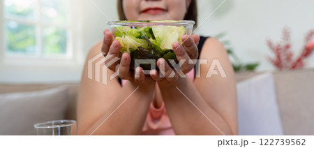 Overweight woman holding a fresh salad, embracing healthy weight loss. Overweight woman holding a fresh salad, embracing healthy weight loss. 122739562