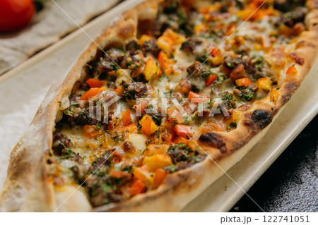 Turkish pide with minced meat, vegetables and cheese on a plate in a stylish restaurant setting Turkish pide with minced meat, vegetables and cheese on a plate in a stylish restaurant setting 122741051