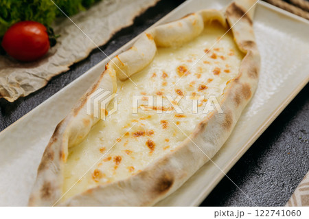 Turkish cheese pide with melted mozzarella on a plate in elegant and traditional food presentation Turkish cheese pide with melted mozzarella on a plate in elegant and traditional food presentation 122741060