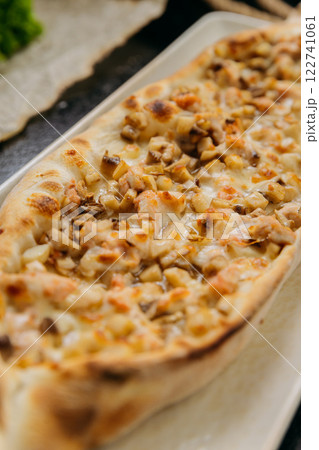 Turkish pide with diced chicken, cheese, and vegetables on plate in traditional gourmet presentation 122741061