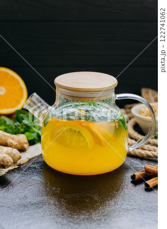 Glass teapot with citrus and ginger herbal tea, infused with fresh mint and cinnamon Glass teapot with citrus and ginger herbal tea, infused with fresh mint and cinnamon 122741062
