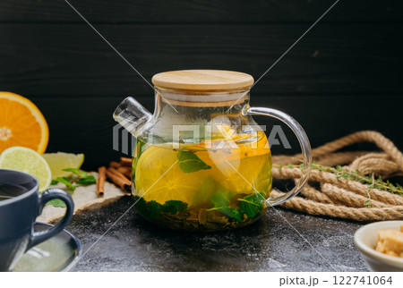 Herbal citrus tea with fresh mint, lime, orange and brown sugar served in a glass teapot and cup Herbal citrus tea with fresh mint, lime, orange and brown sugar served in a glass teapot and cup 122741064