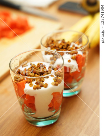 Two glasses of vegetarian yogurt dessert with papaya and granola on a wooden table 122741904