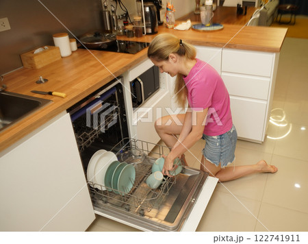 Young woman takes dishes out of the dishwasher machine 122741911