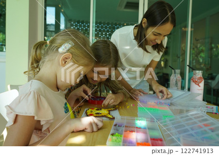Teacher in workshop teched two girls how to assemble a thermo mosaic  122741913